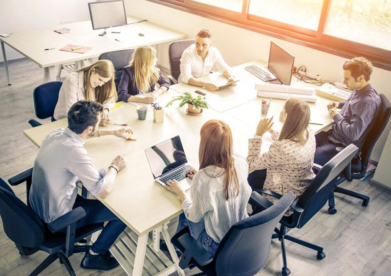 A group of people sitting at tables with laptops.